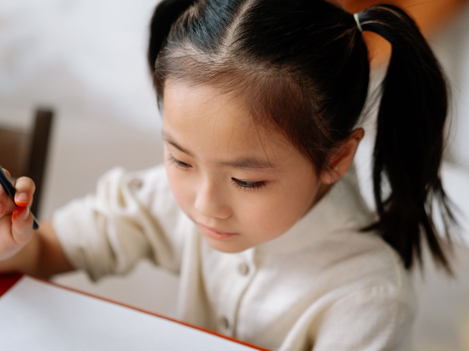 A girl writing carefully with a pencil