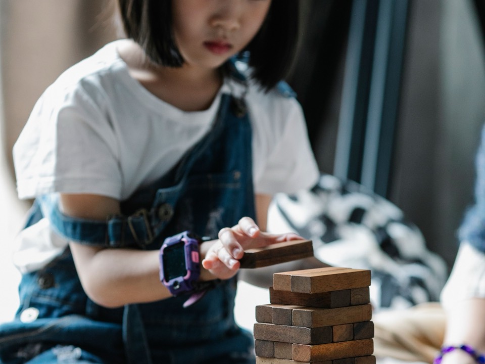 一個女孩小心地堆疊木塊高塔